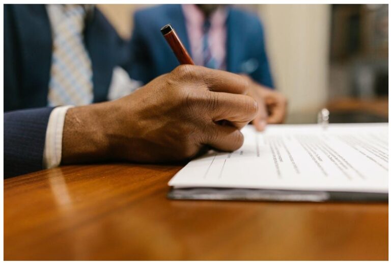 mans hand with pen signing legal contract