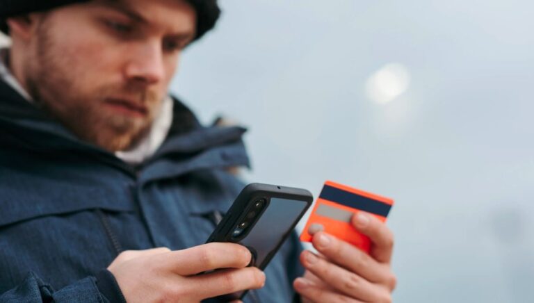 man looking at cell credit card