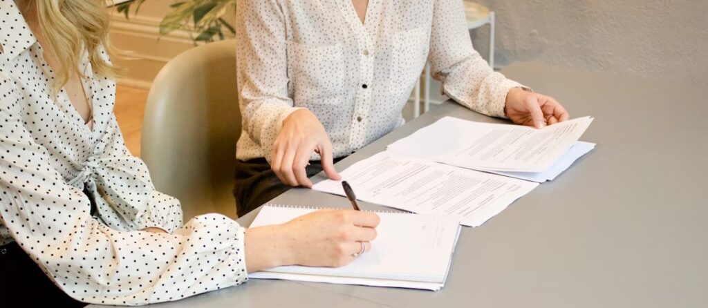 signing documents and making notes two women contract