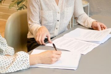 signing documents and making notes two women contract