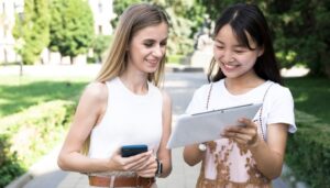 two university girls on tablet and mobile phone