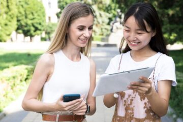 two university girls on tablet and mobile phone