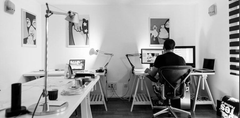 man sitting in front of computer in white room